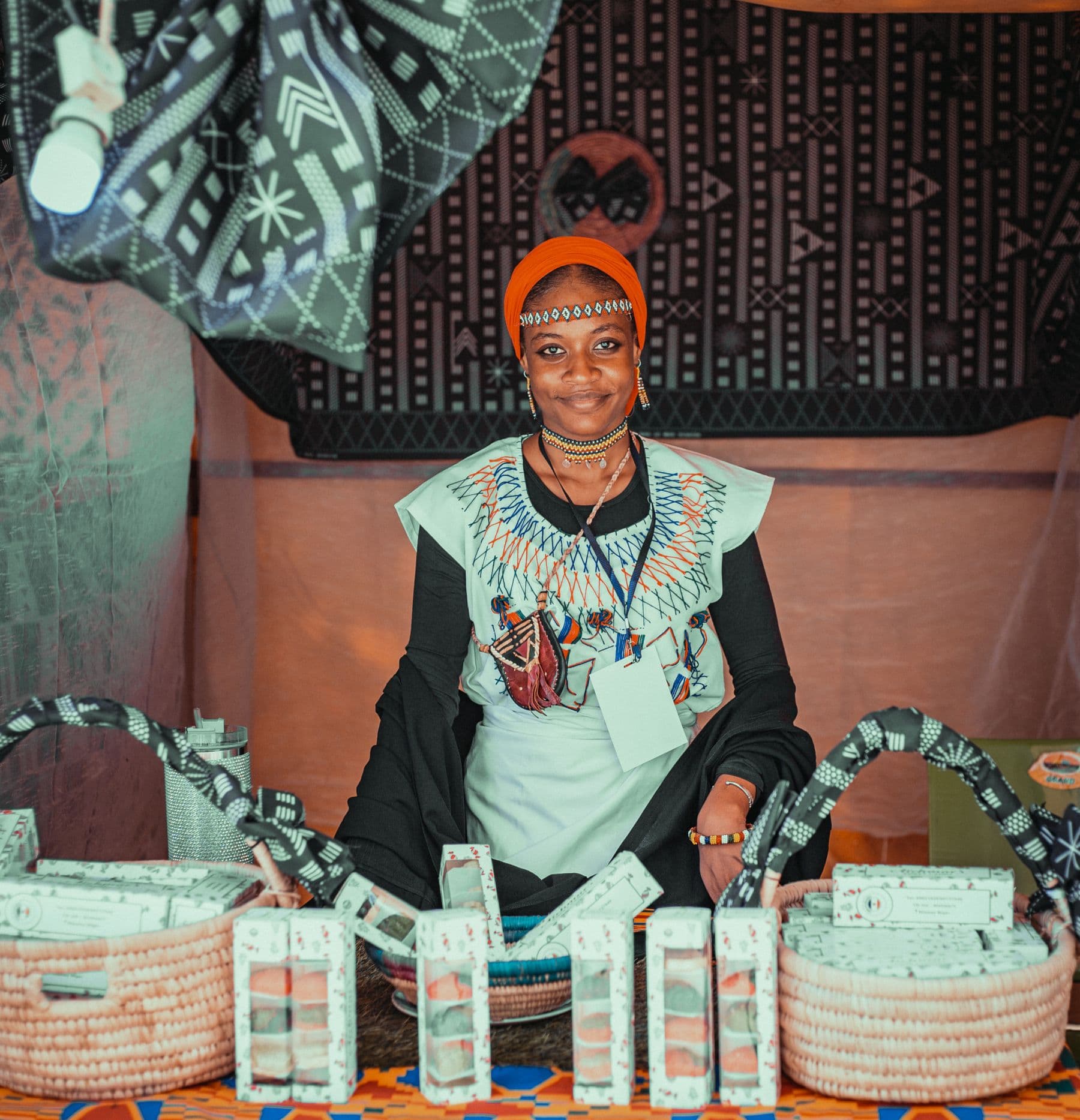 An artisan in traditional attire at her stall of handmade goods