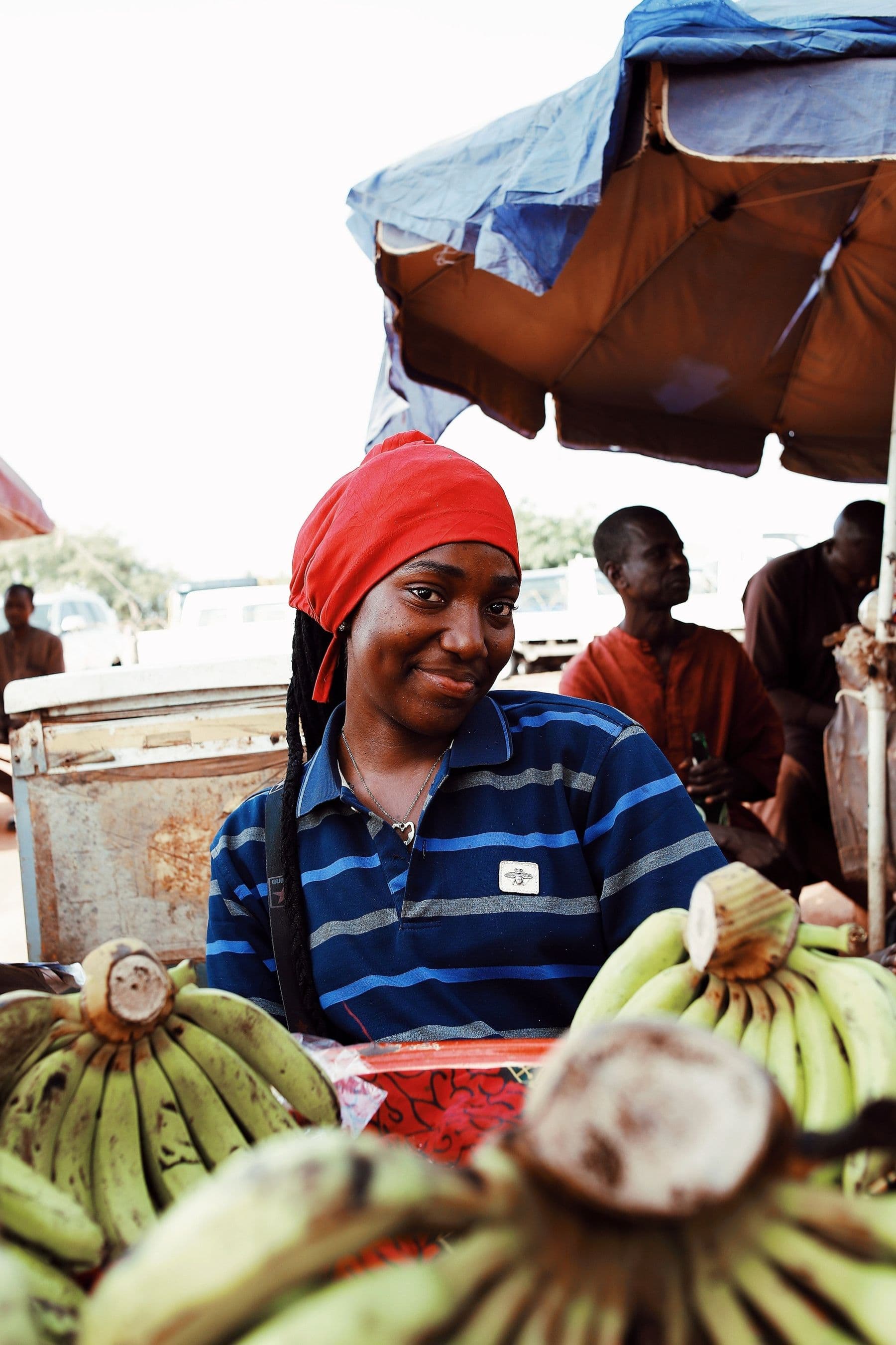 A smiling market trader at her stall of plantains in Abuja